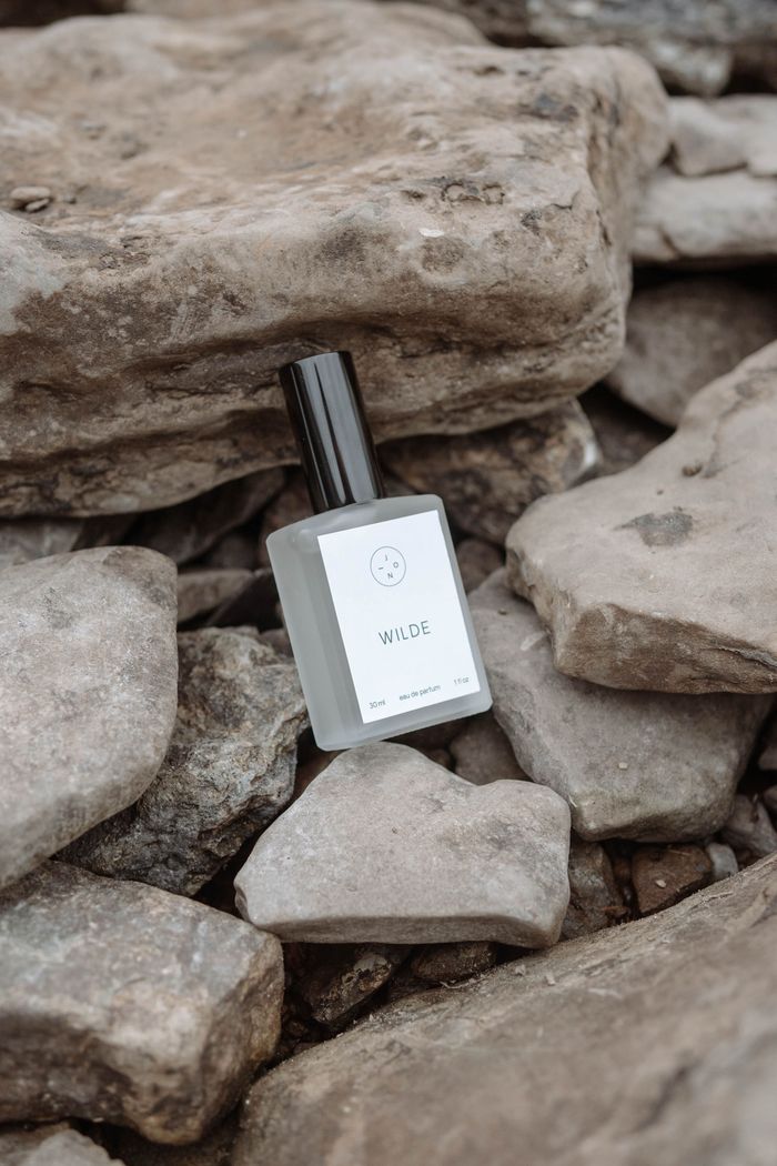 Stylish perfume bottle set on rugged rocks, evokes natural elegance and earthy tones.
